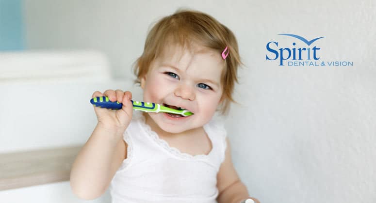 Toddler brushing teeth and smiling.