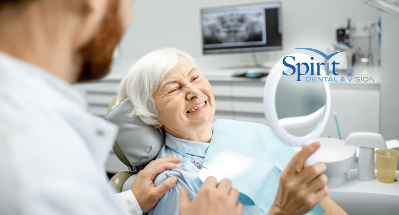 Older lady smiling into a mirror in her dentist's chair