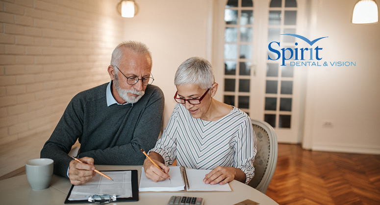 Older couple at kitchen table looking over insurance paperwork