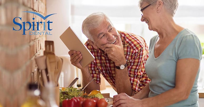 Senior man and woman with great teeth at kitchen counter smiling and gazing at each other fondly