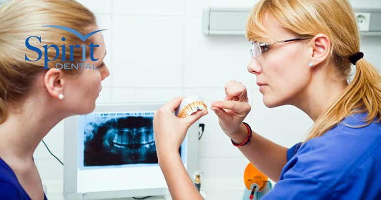 Dentist showing lady her first dental implant