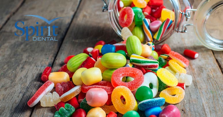 Jar of candy on it's side with candy falling out of it onto the table