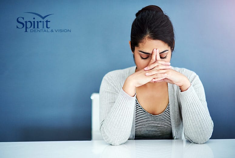 A lady with her head down at a table trying to overcome dental anxiety