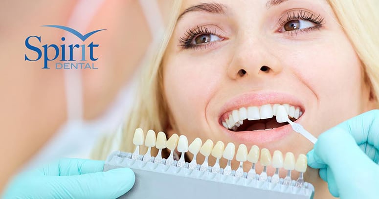 Dentist holding porcelain crowns to match the color of the ladies teeth in the chair