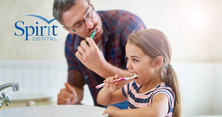 Father and daughter brushing teeth together