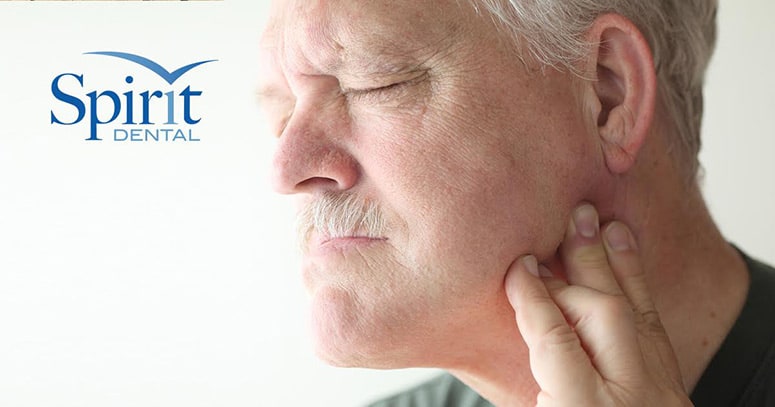 Man in pain holding his jaw with tmj syndrome