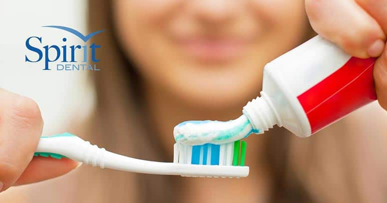 Up-close photo of a lady putting toothpaste onto a toothbrush