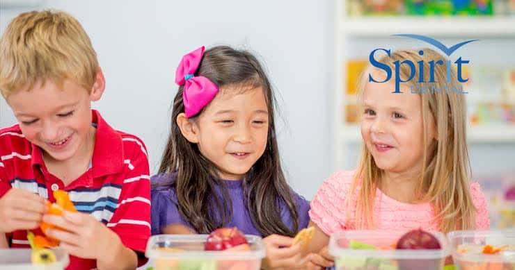 3 kids at a table with their packed lunches